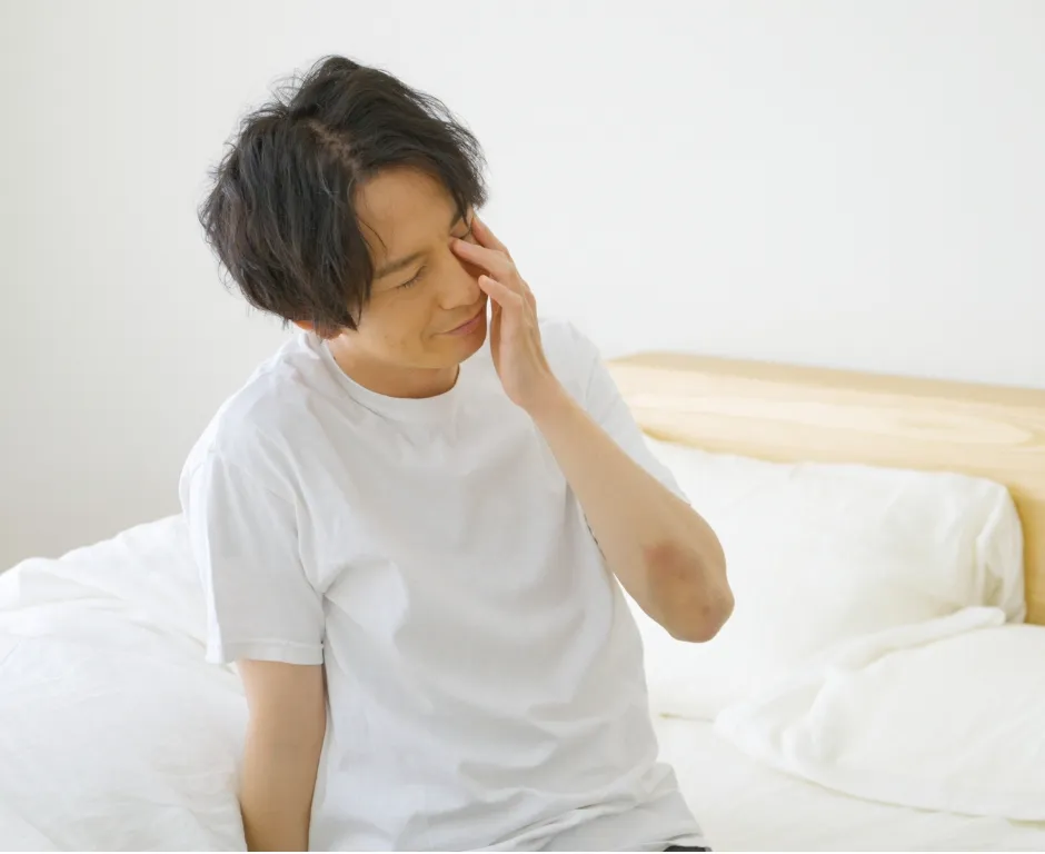 ベッドで頭を抱える男性